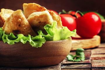 Homemade fried little pies with meat in a bowl, vintage wooden b