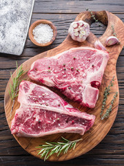 Steak T-bone with spices on the wooden cutting board.