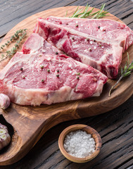 Steak T-bone with spices on the wooden cutting board.