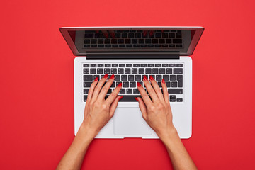 Fototapeta na wymiar Woman typing on a laptop keyboard on red flat lay background