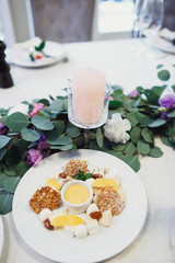 Tasty pastry, fruits and cream on white plate before green garla