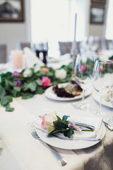 Pink rose lies on white serviette on dinner plate
