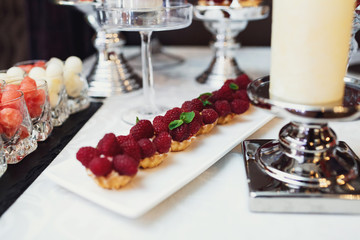Baked basckets with cream and raspberry stand on square plate