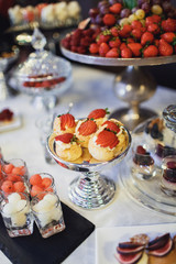 Little steel dish with eclairs and slices of strawberries on the