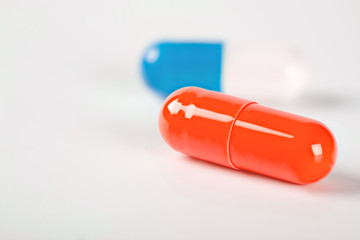 Two medical pills blue and yellow with shadows