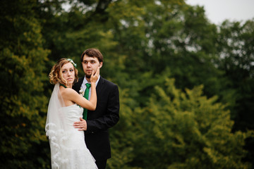 Fototapeta premium Embracing wedding couple in love on cloudy weather outdoor.