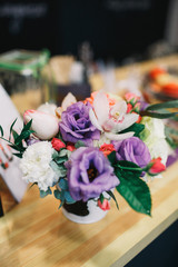 Little bouquet of violet flowers stands on wooden table