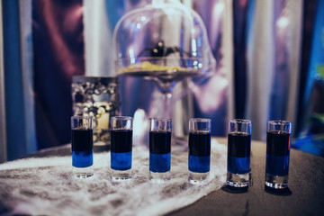 Black and blue drinks on black table with decorative web