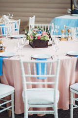 White chairs stand aroun pink dinner table with wooden box of fl