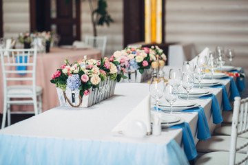 Blue wedding dinner table decorated with wooden boxes of roses