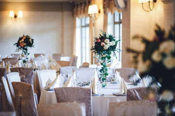 Tables covered with beige cloth and decorated with white rose bo