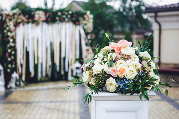 Pillar with rose bouquet on top stands before wedding altar outs