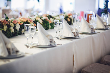 Dinner plates with serviettes and little present boxes stand on
