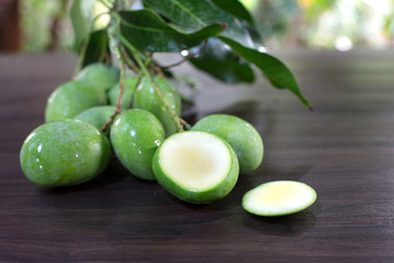 Bunch of fresh Mangoes on the brown table in green garden