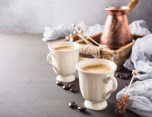 Coffee cups and old coffee pot on dark brown background with copy space.