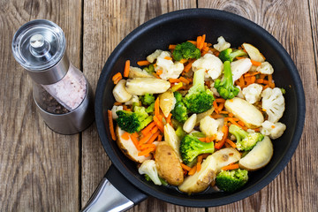 Mixed vegetables frying pan on background of old boards