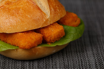 fish fingers sticks in bun with salad, closeup, low focus on gra