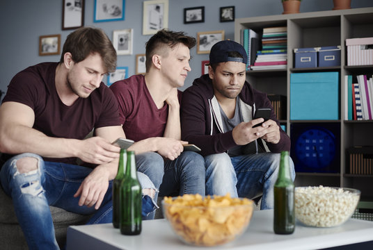 Close up of men with smartphones in the living room