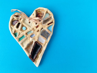 Ceramics heart on blue background. Handmade object of art.