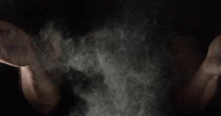SLOW MOTION closeup of an athlete hands clapping with white chalk powder