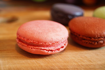 macaroon dessert with colored fillings lie on a wooden table