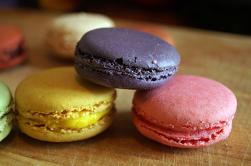 macaroon dessert with colored fillings lie on a wooden table