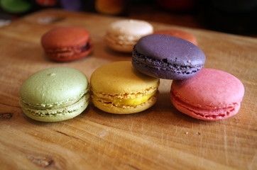 macaroon dessert with colored fillings lie on a wooden table
