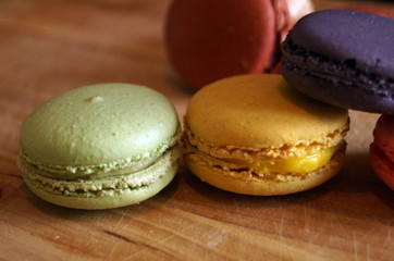 macaroon dessert with colored fillings lie on a wooden table