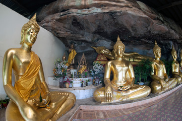 Row of golden Buddha statues in a cave at  Buddhist temple.