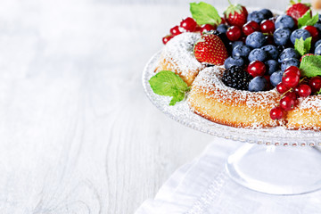 Sponge cake with fresh berries on white table with free text space.