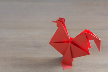 red origami chicken on wooden background