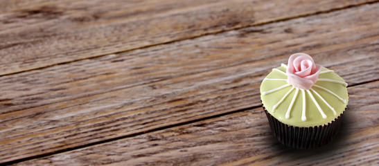 cupcake with rose on wooden background