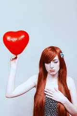 Chica triste sujetando un globo de corazón en san valentín 