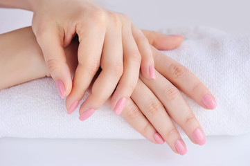 Hands of a woman with pink manicure are on a towel