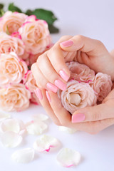 Hands of a woman with pink manicure on nails and roses