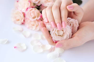 Tischdecke Hände einer Frau mit rosafarbener Maniküre auf Nägeln und Rosen © nmelnychuk