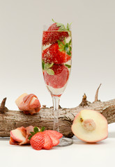 Champagne cocktail filled with strawberries and surrounded by peaches