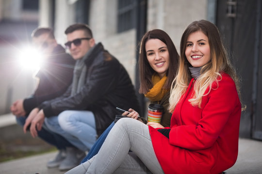 Young friends sitting outdoors and posing in front of a camera