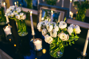 The vases with flowers and candles stand on the commode