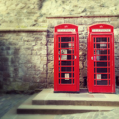 A pair of traditional Britsh red phone boxesagainst the wall of Edinburgh Castle, Scotland.