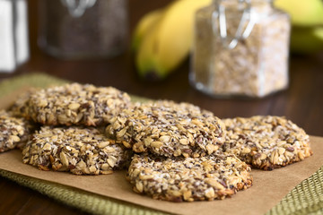 Vegan cookies made of banana, oatmeal, roasted oat grain, linseed, poppy seed, grated coconut, chia seed and cinnamon, photographed with natural light (Selective Focus on the front of the top cookie)