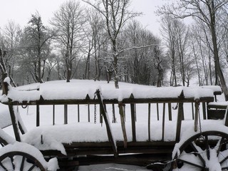 snowy historic wooden wagon standing on a rural farm