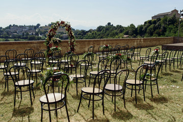 Wooden chairs stand in rows on green lawn before wedding altar
