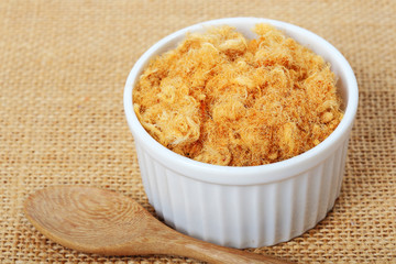 dried pork floss in white cup with wooden spoon on sack