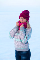 Portrait of young girl in pink hat and scarf in the winter fores