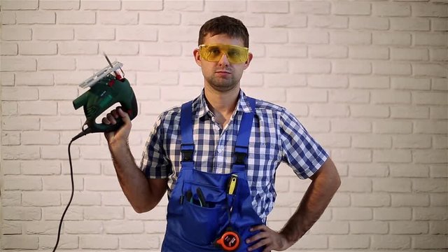 Man with an electric jig saw.  Working with electric jig saw. Construction worker with a power tool. Man makes repairs