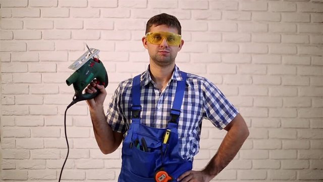 Man with an electric jig saw.  Man makes repairs.  Working with electric jig saw. Construction worker with a power tool. 