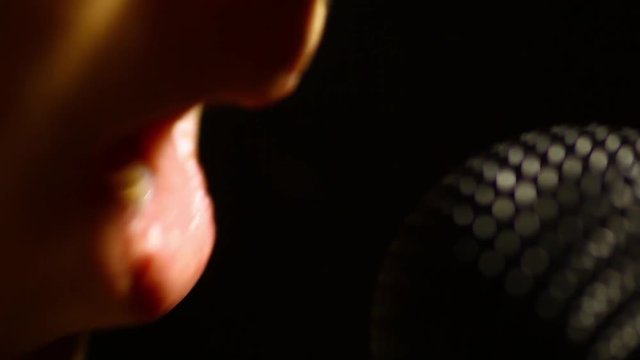 Close up footage of a woman singing to a microphone.