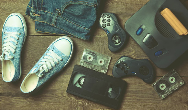 Back in the 90s. Shoes, audio tapes, video tapes, game console, jeans. Top view. Flat lat concept.