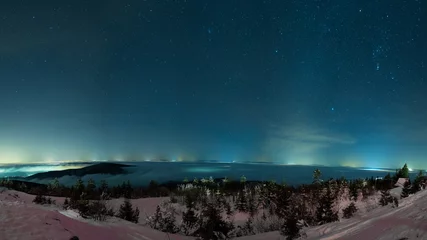 Keuken spatwand met foto winter night sky above mountains with stars and city lights in the distance © lukasx
